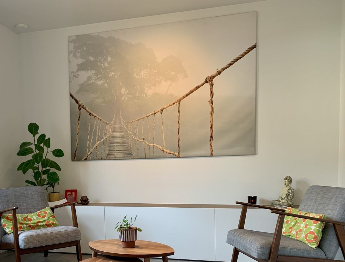 Een canvas van een touwbrug in de mist, aan de muur van de spreekkamer
