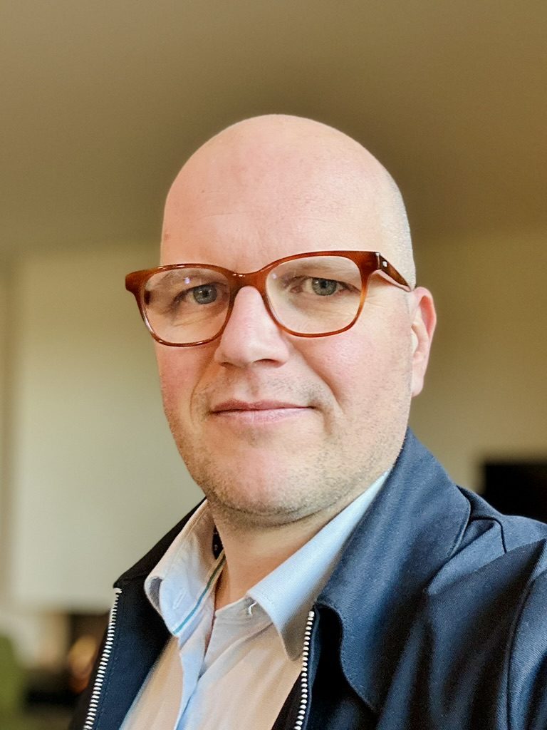 Portret van Jan Jacobs, binnen, met een rustige glimlach