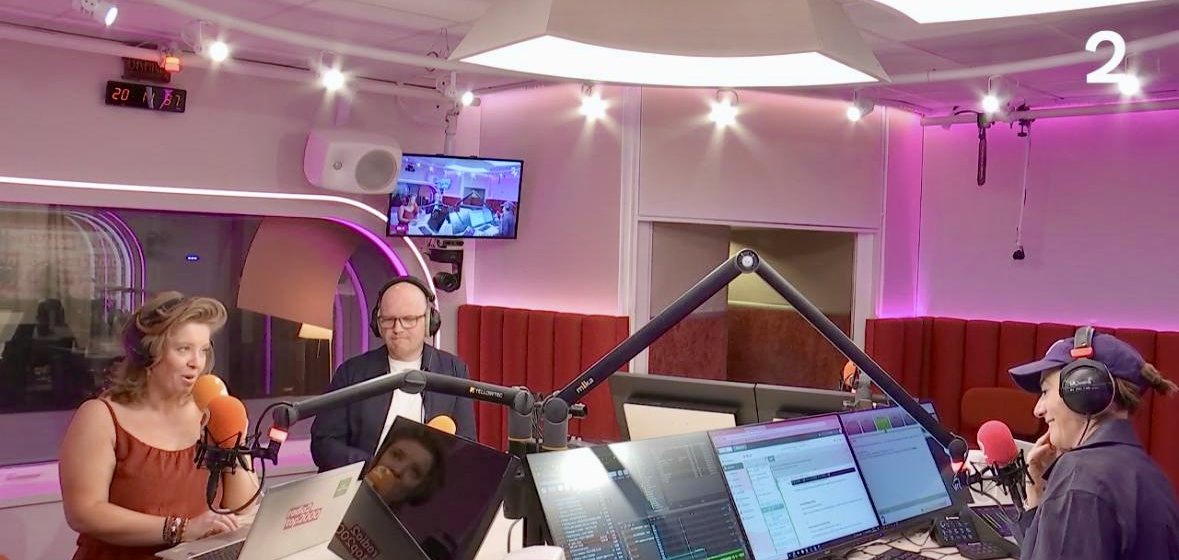 Jan Jacobs met een koptelefoon in de studio van Radio 2, aan tafel met de presentatrice en de technica